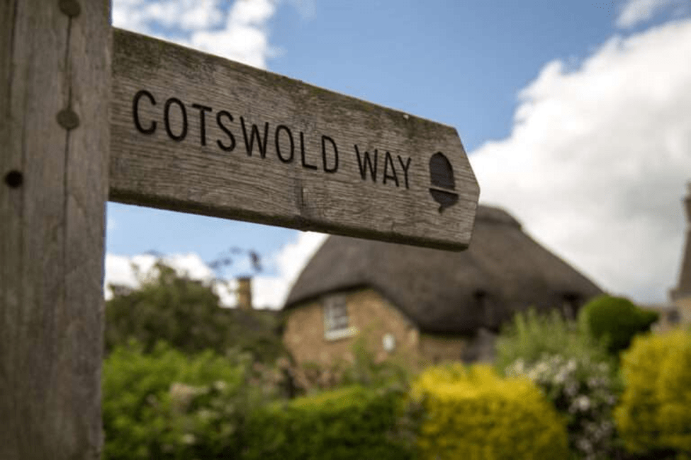 Cotswold Way signpost with traditional thatched cottage in background