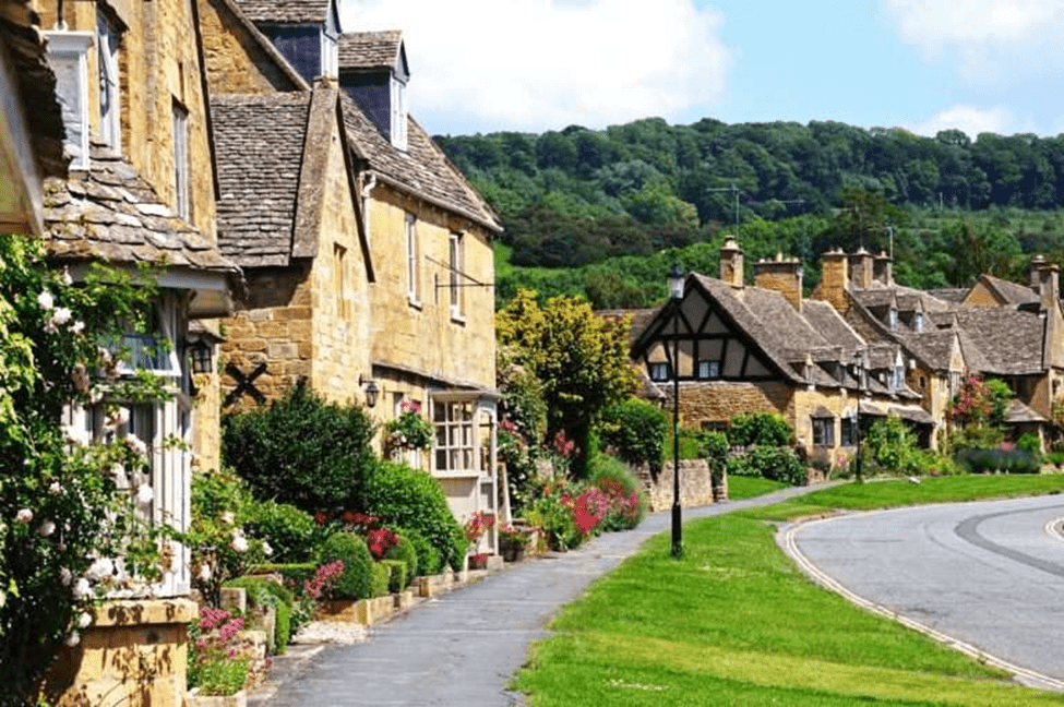 Beautiful Cotswold village street with stone cottages and flower gardens